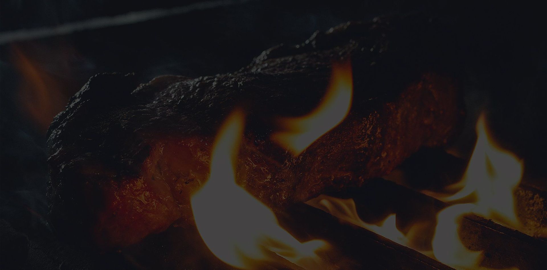 Frisches Steak wird auf einem Rost direkt über Feuer gegrillt